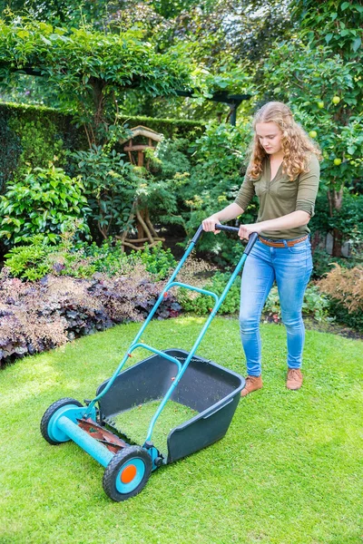 Young dutch woman pushing lawn mower on grass — Stock Photo, Image