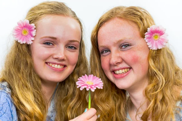 Två systrar med rosa blommor i långt hår — Stockfoto