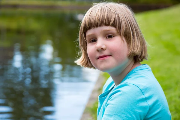 年轻的女孩坐在池塘 — 图库照片