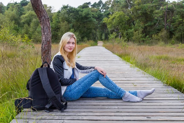 Menina loira descansando no caminho de madeira na natureza — Fotografia de Stock