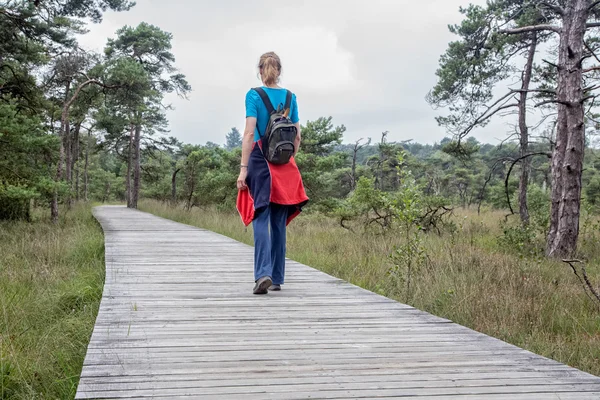 Woman hiking on wooden path in nature — Stock Photo, Image