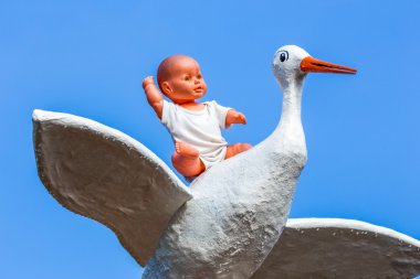 Leylek mavi gökyüzü ile oturan oyuncak bebek