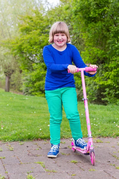 Jong meisje permanent met roze scooter — Stockfoto