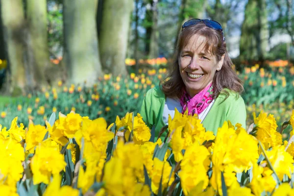 Frau sitzt hinter Narzissenfeld — Stockfoto