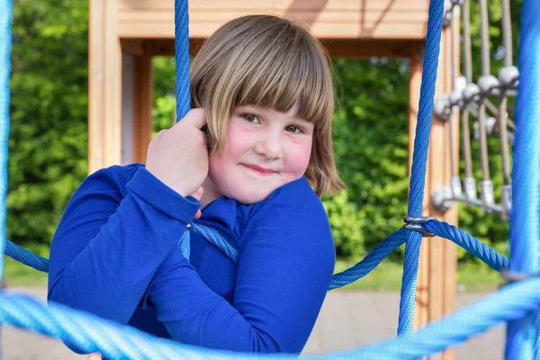 Junges Mädchen hängt in Netz aus blauen Seilen — Stockfoto