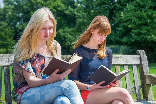 Dwie dziewczyny czytanie książek na ławce w przyrodzie — Zdjęcie stockowe