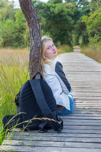 Doğada ahşap yolu üzerinde oturan kız — Stok fotoğraf