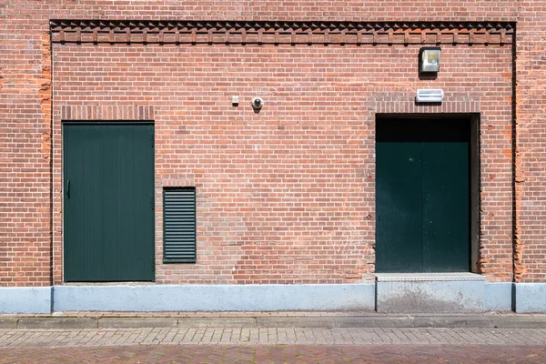 Old brick wall with doors and street — Stock Photo, Image