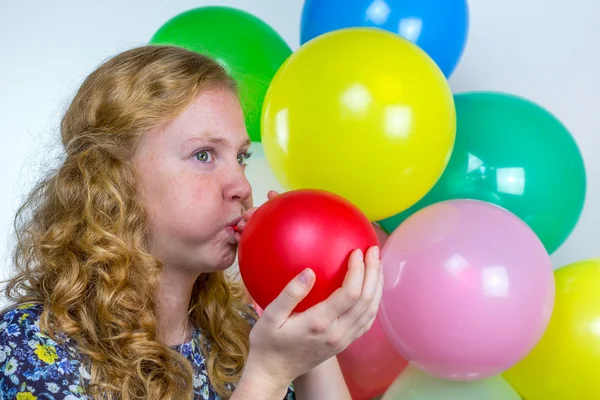 Chica soplando inflando globos de colores — Foto de Stock