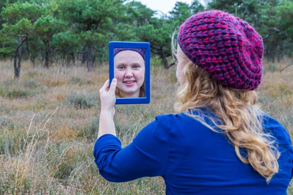 Girl looking in mirror in nature — Stock Photo, Image