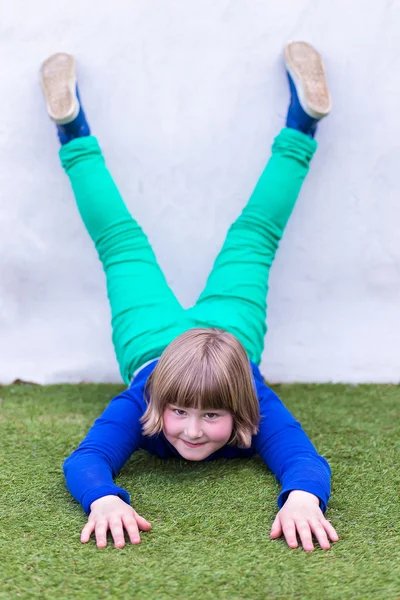 Young girl lying upside down against wall — Stock Photo, Image