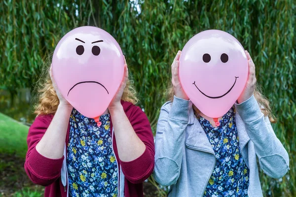 Duas meninas segurando balões com expressões faciais — Fotografia de Stock