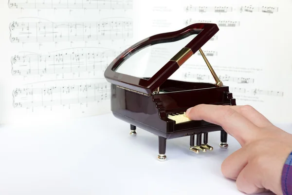 Dedos tocando en un pequeño modelo de piano de cola — Foto de Stock