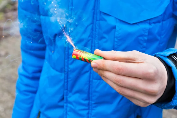 Hand holding burning firework in front of blue jacket — Stock Photo, Image