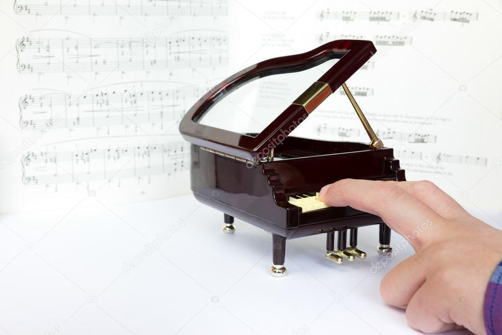 Fingers playing on small model of grand piano