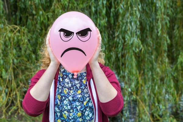 Девушка держит воздушный шар с сердитым лицом — стоковое фото