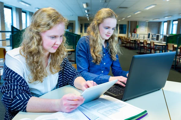 Dvě holandské dívky pracující na počítači a tablet v počítačové učebně — Stock fotografie