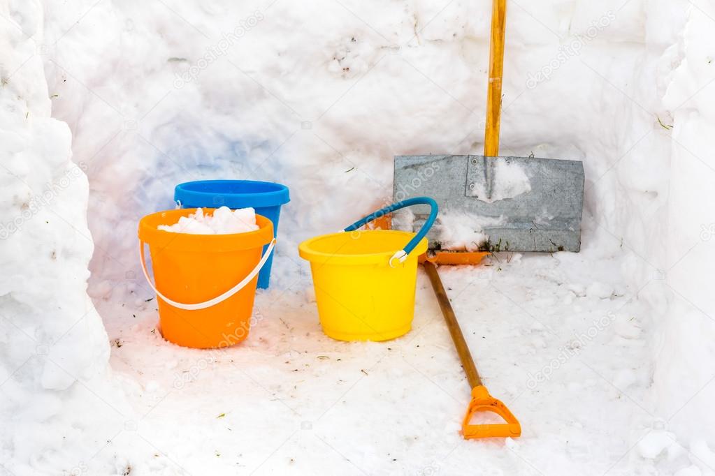 Hut with walls of snow and colorful buckets plus snowplow