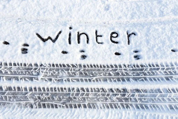 Word winter and tire tracks in snow — Stock Photo, Image