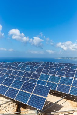 Field of solar collectors near sea with blue sky