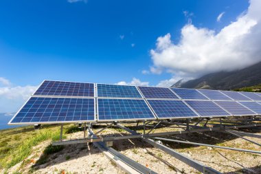 Row of solar collectors on mountain with blue sky