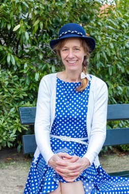 Dutch woman in old-fashioned clothes sitting on bench in park