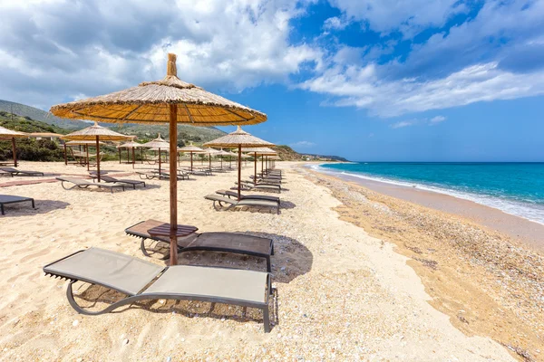 Beach umbrellas in rows on sandy beach with sea — Stock Photo, Image