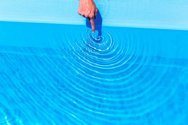 Forefinger making waves as circles in swimming pool