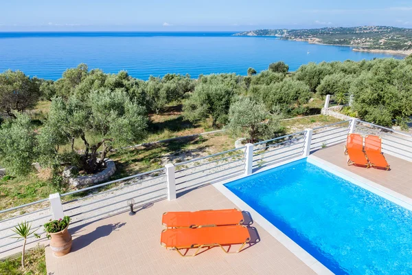 Chaises longues sur terrasse avec piscine près de la mer — Photo