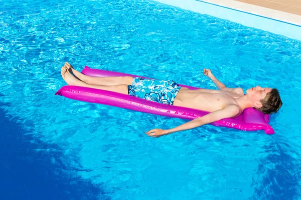 Dutch teenage boy lying  on air mattress in swimming pool — Stock Photo, Image