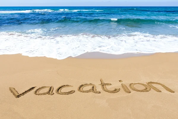 Word vacation written in sand of beach at sea — Stock Photo, Image