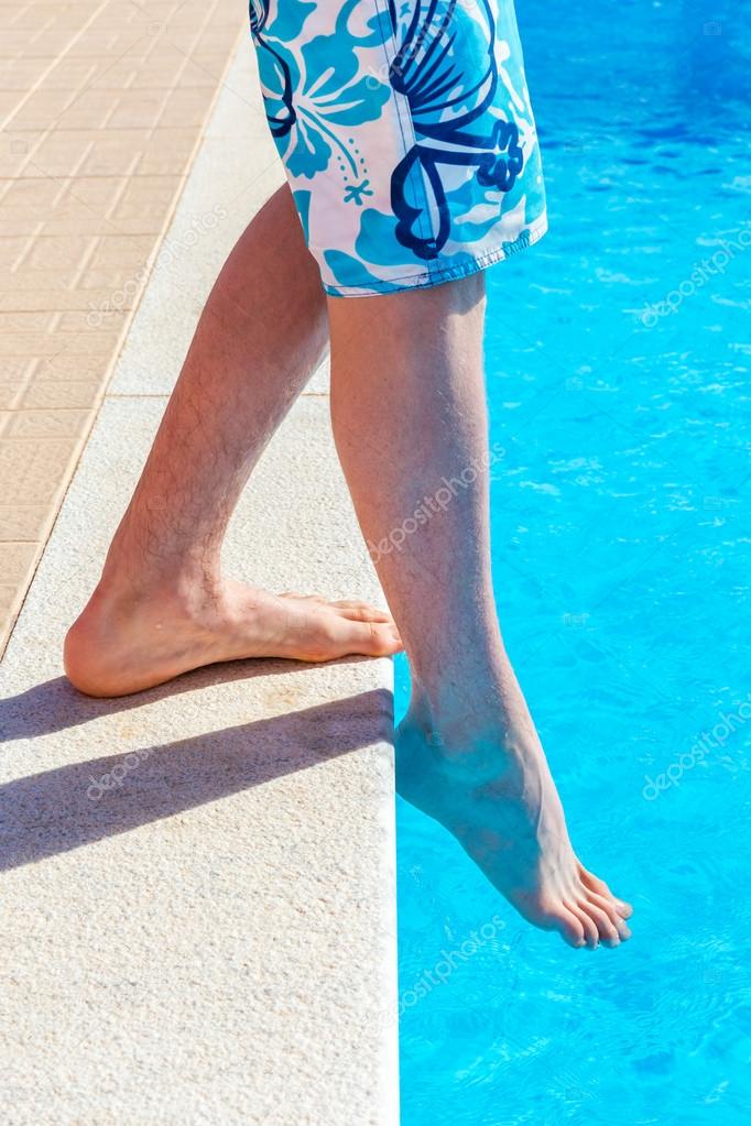Legs with foot feeling water temparature in swimming pool