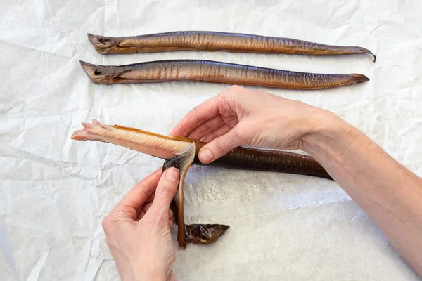 Mains femelles enlevant la peau préparant les anguilles — Photo