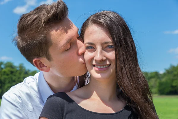 Freund küsst Freundin in sonniger Natur auf die Wange — Stockfoto