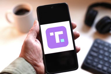 VALENCIA, İspanya 01.27, 2026. Bir el, canlı yeşil ekranda çizgi logosunu gösteren akıllı telefonu kavrıyor. Modern bir çalışma ortamında mobil mesajlaşma, bağlantı ve dijital iletişimi öneriyor..
