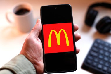 VALENCIA, İspanya 01.27, 2026. Bir el, canlı yeşil ekranda çizgi logosunu gösteren akıllı telefonu kavrıyor. Modern bir çalışma ortamında mobil mesajlaşma, bağlantı ve dijital iletişimi öneriyor..