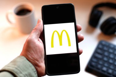 VALENCIA, İspanya 01.27, 2026. Bir el, canlı yeşil ekranda çizgi logosunu gösteren akıllı telefonu kavrıyor. Modern bir çalışma ortamında mobil mesajlaşma, bağlantı ve dijital iletişimi öneriyor..