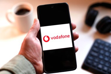 VALENCIA, İspanya 01.27, 2026. Bir el, canlı yeşil ekranda çizgi logosunu gösteren akıllı telefonu kavrıyor. Modern bir çalışma ortamında mobil mesajlaşma, bağlantı ve dijital iletişimi öneriyor..