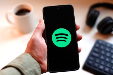 VALENCIA, İspanya 01.27, 2026. Bir el, canlı yeşil ekranda çizgi logosunu gösteren akıllı telefonu kavrıyor. Modern bir çalışma ortamında mobil mesajlaşma, bağlantı ve dijital iletişimi öneriyor..