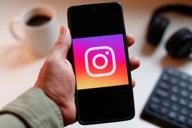 VALENCIA, İSPA 01.27, 2026: Bir el, modern bir çalışma ortamında mobil mesajlaşma, bağlantı ve dijital iletişimi öneren canlı yeşil ekranda hat logosunu gösteren bir akıllı telefonu kavrıyor.