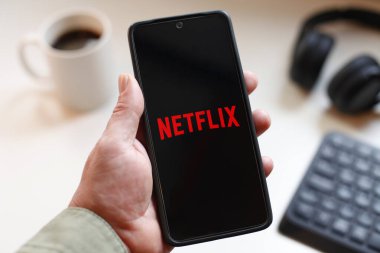 VALENCIA, İSPA 01.27, 2026: Bir el, modern bir çalışma ortamında mobil mesajlaşma, bağlantı ve dijital iletişimi öneren canlı yeşil ekranda hat logosunu gösteren bir akıllı telefonu kavrıyor.