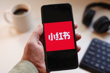 VALENCIA, İSPA 01.27, 2026: Bir el, modern bir çalışma ortamında mobil mesajlaşma, bağlantı ve dijital iletişimi öneren canlı yeşil ekranda hat logosunu gösteren bir akıllı telefonu kavrıyor.