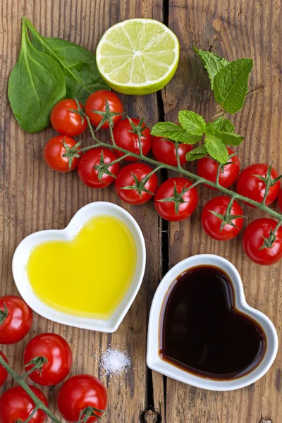 Oil and vinegar in heart shaped bowls displayed with fresh produ — Stock Photo, Image