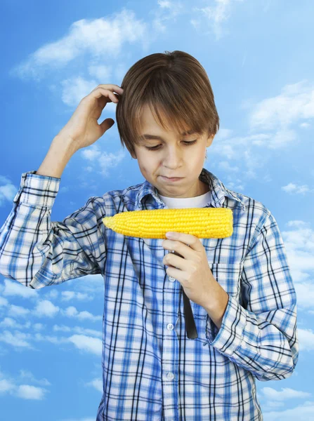 Boy memegang jagung rebus di latar belakang langit biru — Stok Foto