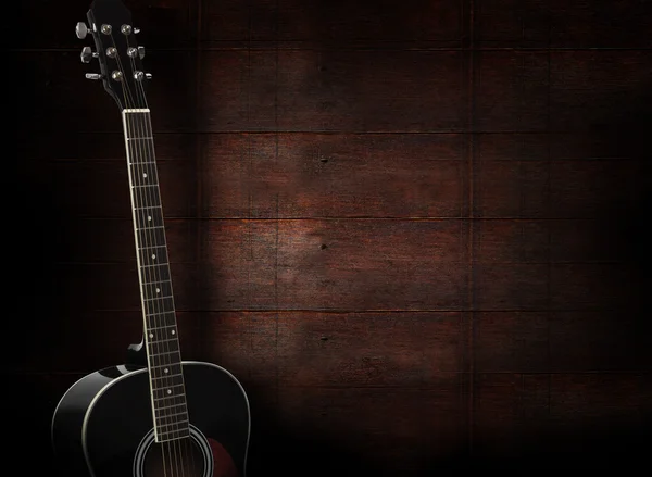 Koyu kırmızı ahşap arka plan üzerinde siyah akustik gitar.