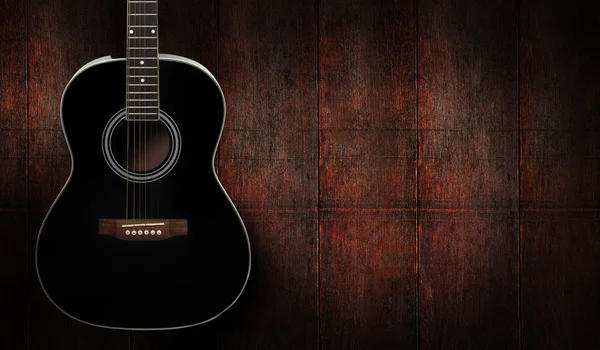 Koyu kırmızı ahşap arka plan üzerinde siyah akustik gitar.