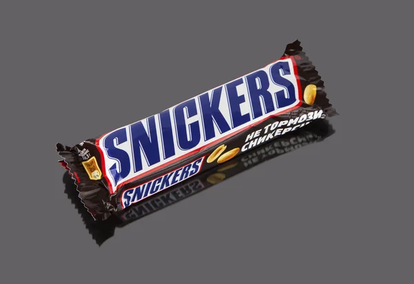 Barra de chocolate Snickers sobre un fondo gris — Foto de Stock