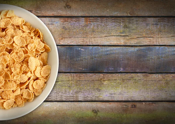 Corn flakes in a plate on a wooden table