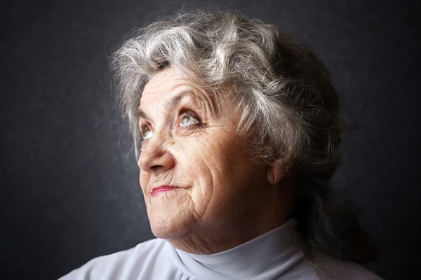 Cara de abuela pensativa sobre un fondo oscuro — Foto de Stock