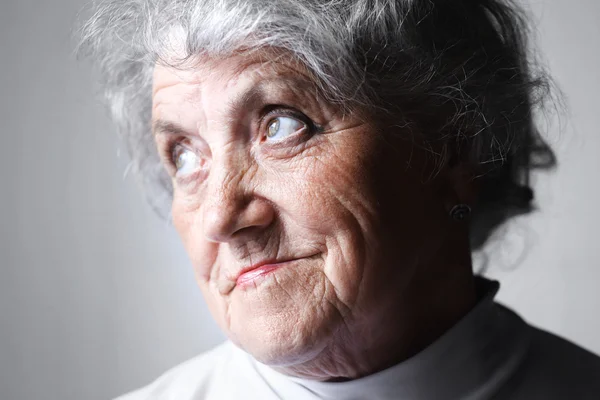 Olhando retrato de mulher velha em um fundo cinza — Fotografia de Stock